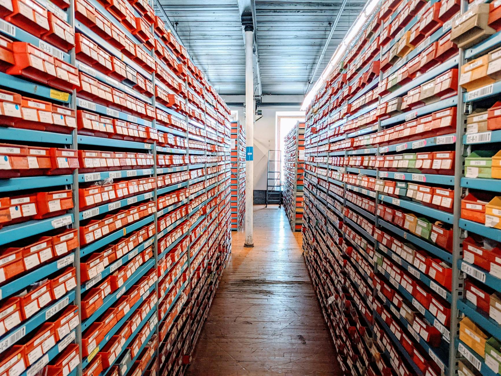 Zorganizowany regał magazynowy z czerwonymi pudełkami z butami