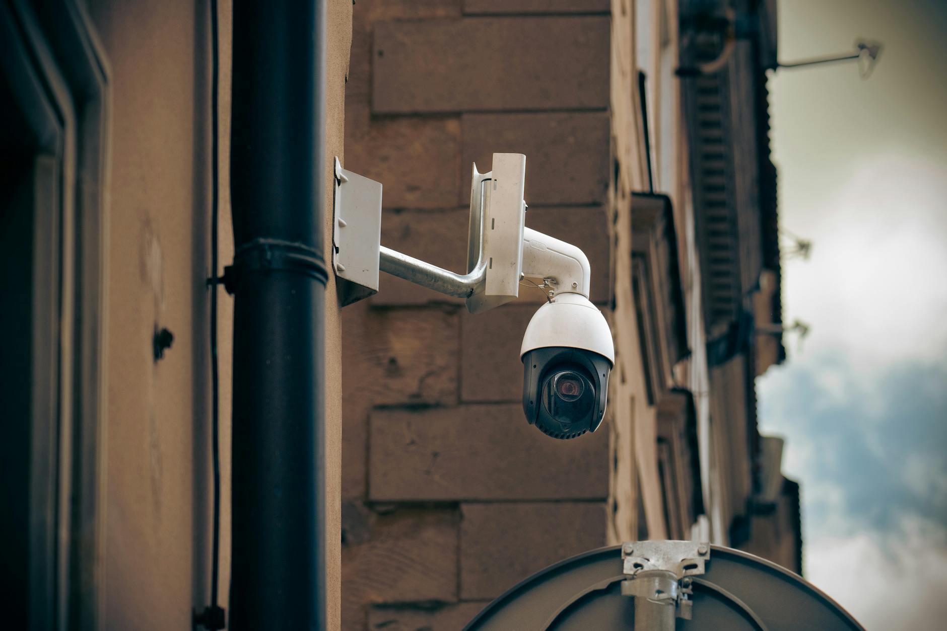 Kamera CCTV na ścianie budynku przy ruchliwej ulicy miejskiej