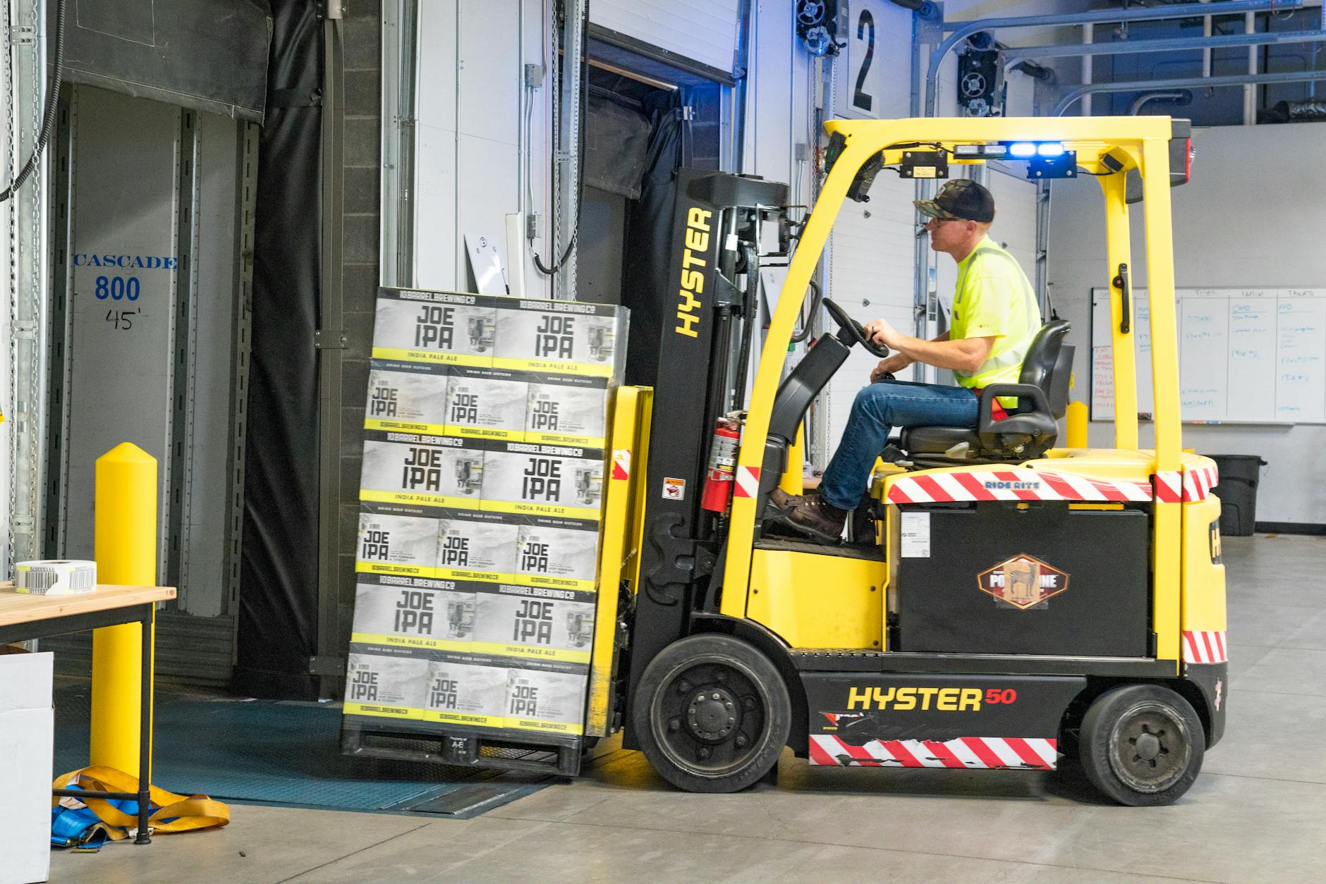 Operator prowadzi wózek widłowy Hyster z kartonami w magazynie
