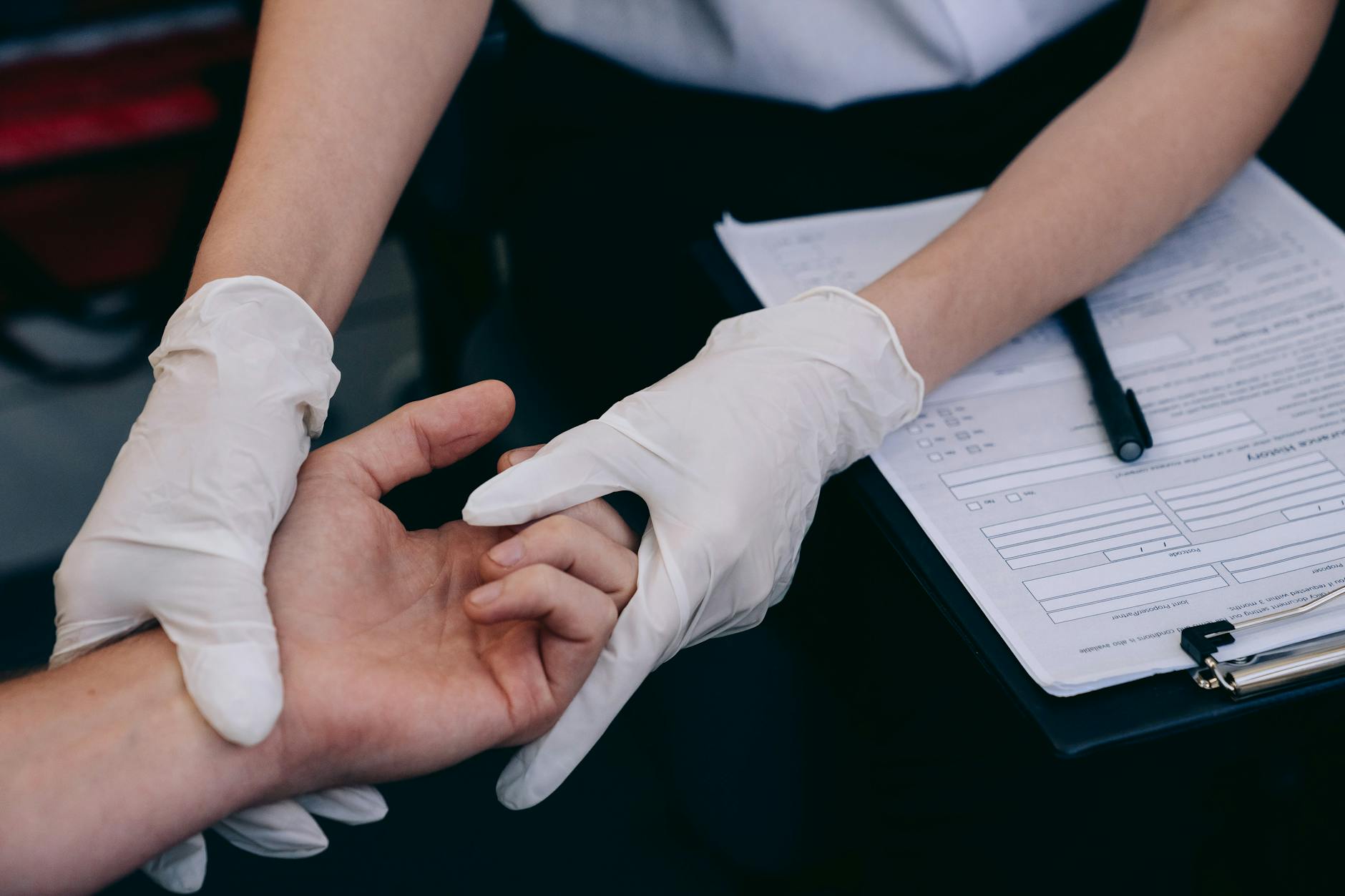 Lekarz w rękawiczkach bada dłoń pracownika podczas badania okresowego