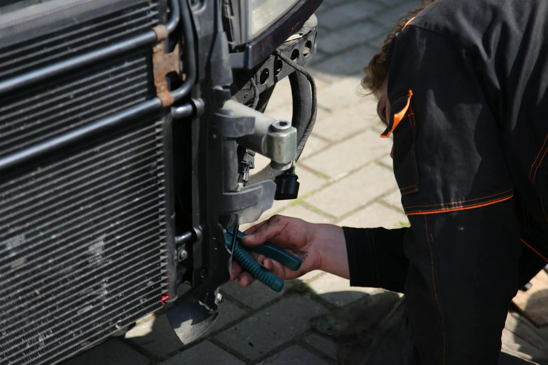 Mechanik na zewnątrz naprawia chłodnicę samochodu narzędziami