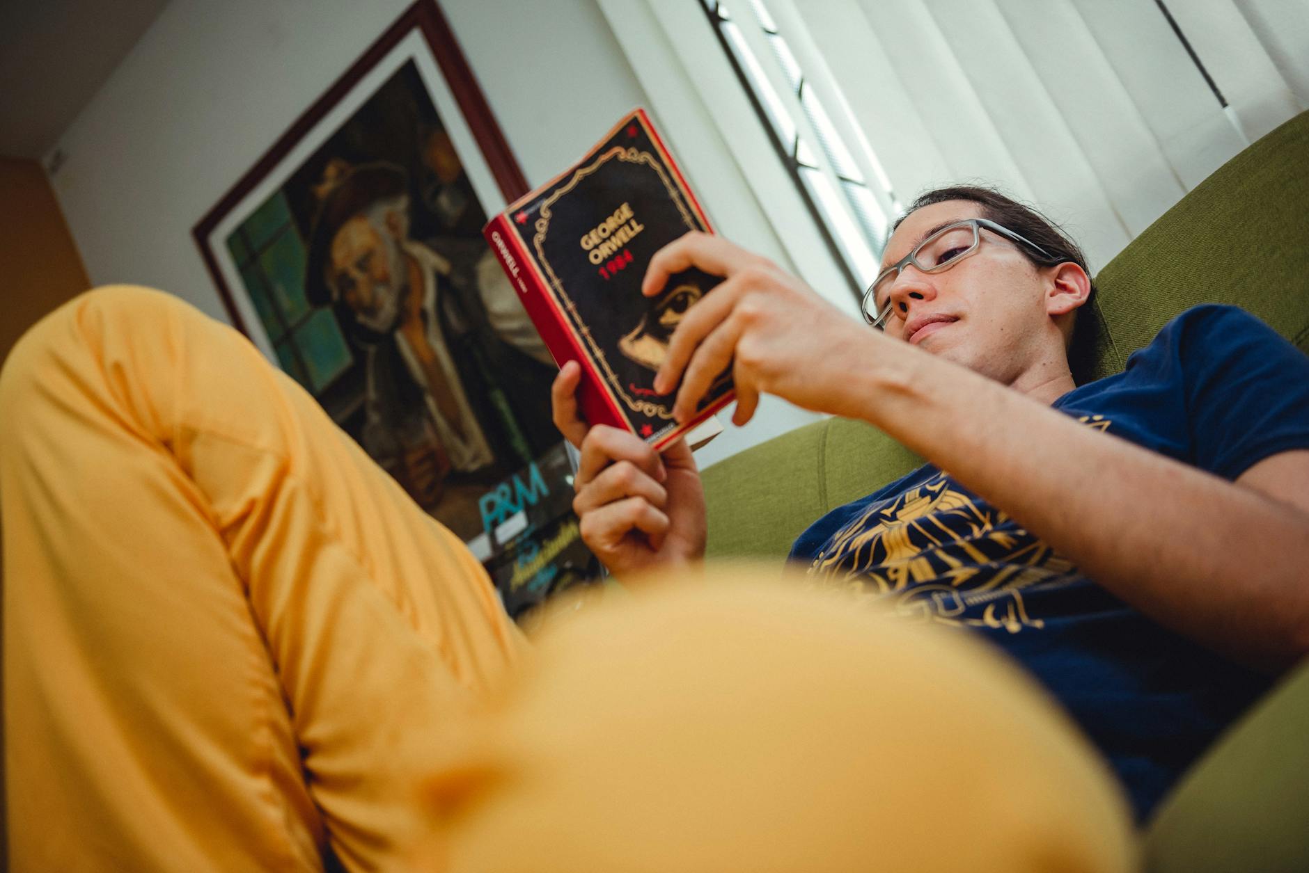 Mężczyzna w okularach czyta powieść w domowym zaciszu