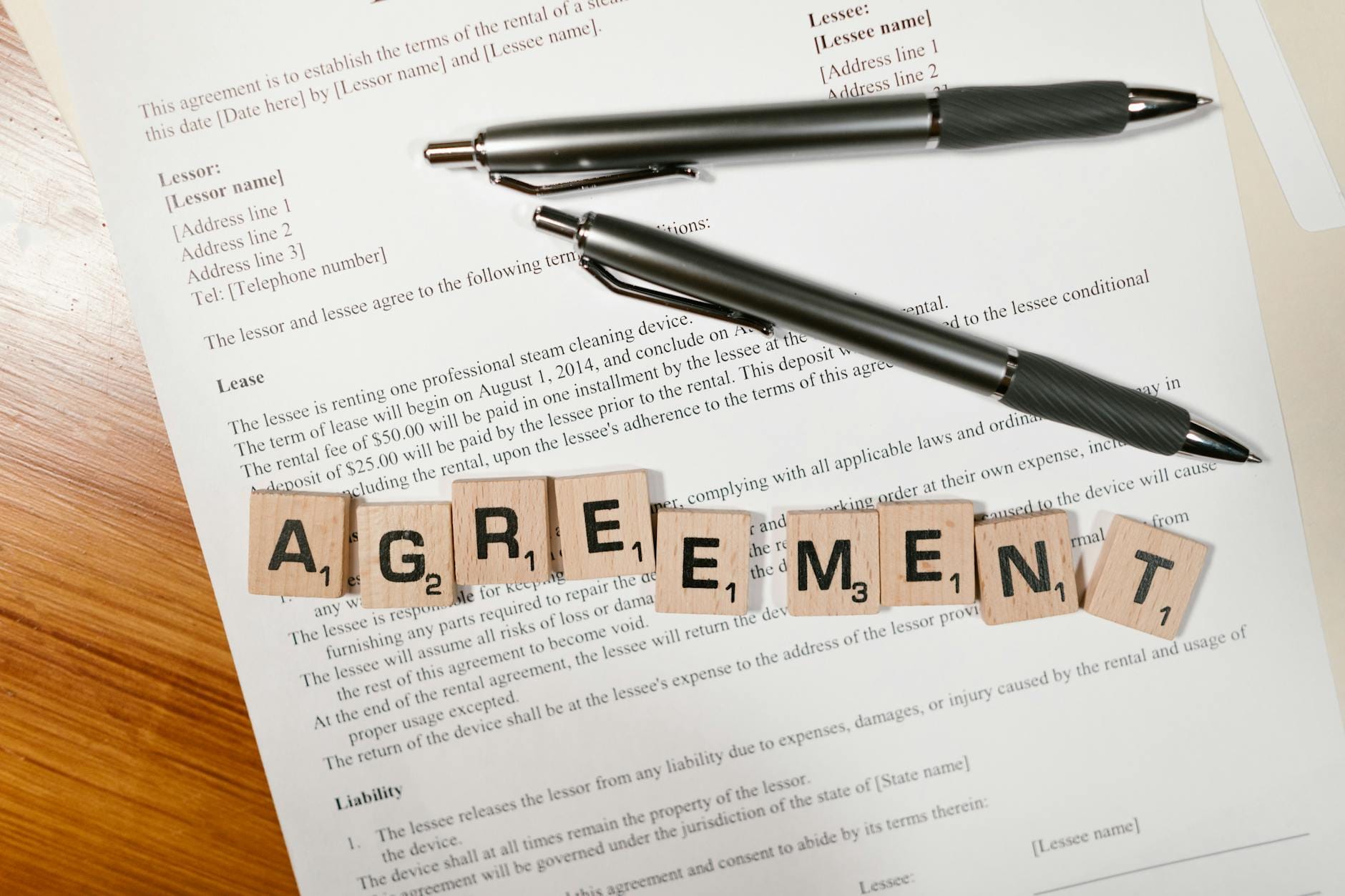Dokument z literkami układającymi się w słowo AGREEMENT i dwiema długopisami