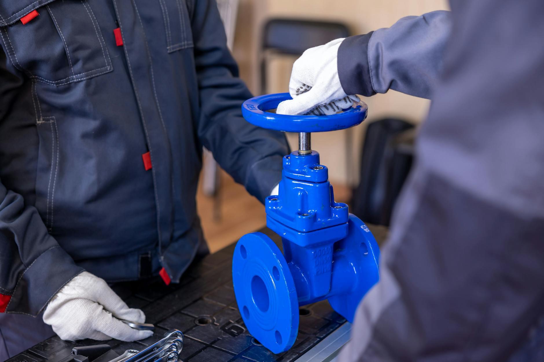 Dwaj serwisanci regulują niebieski zawór hydrauliczny w warsztacie
