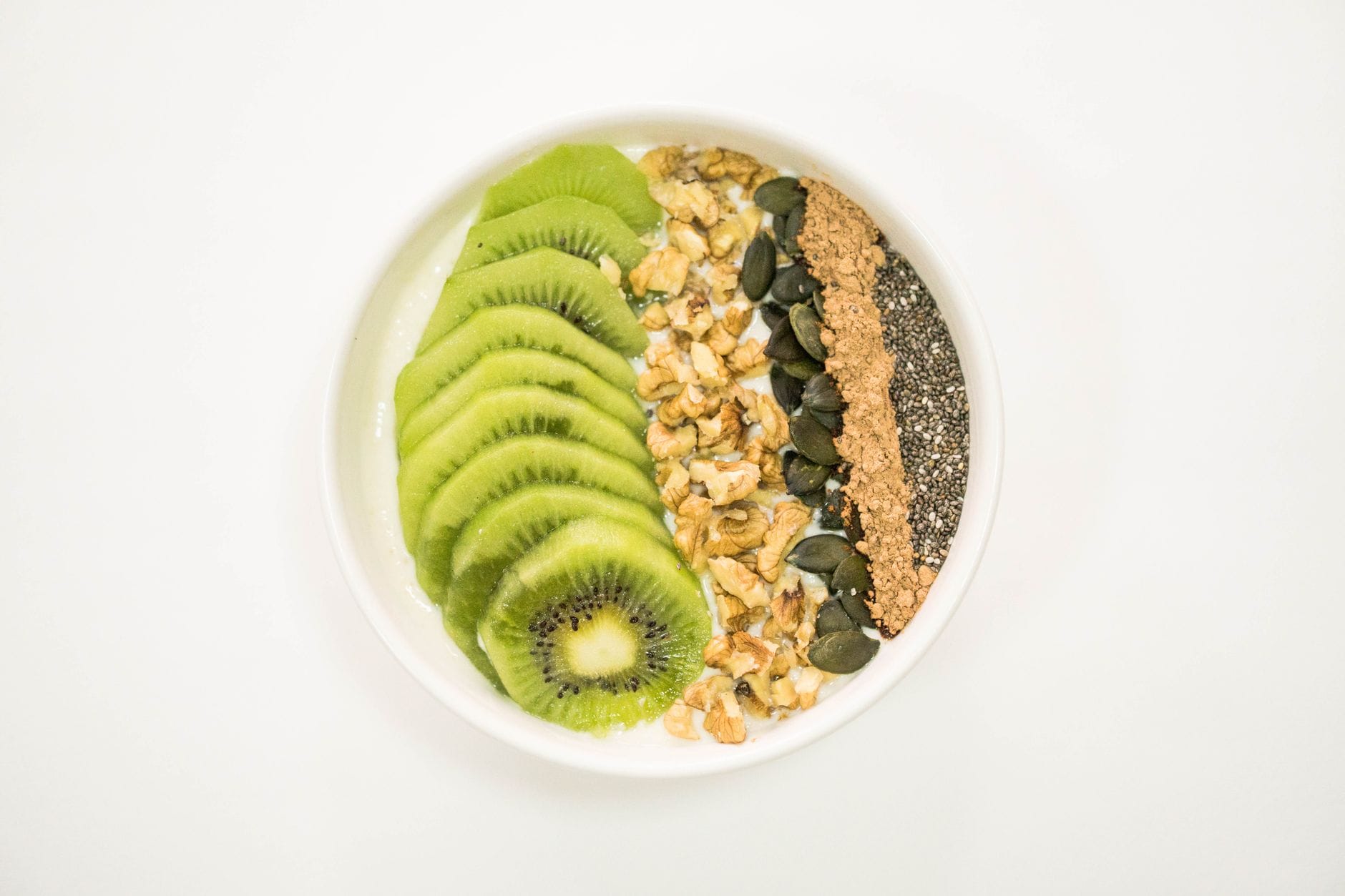 Miska smoothie z kiwi, orzechami, nasionami i jogurtem jako zdrowe śniadanie Miska smoothie z kiwi, orzechami, nasionami i jogurtem jako zdrowe śniadanie