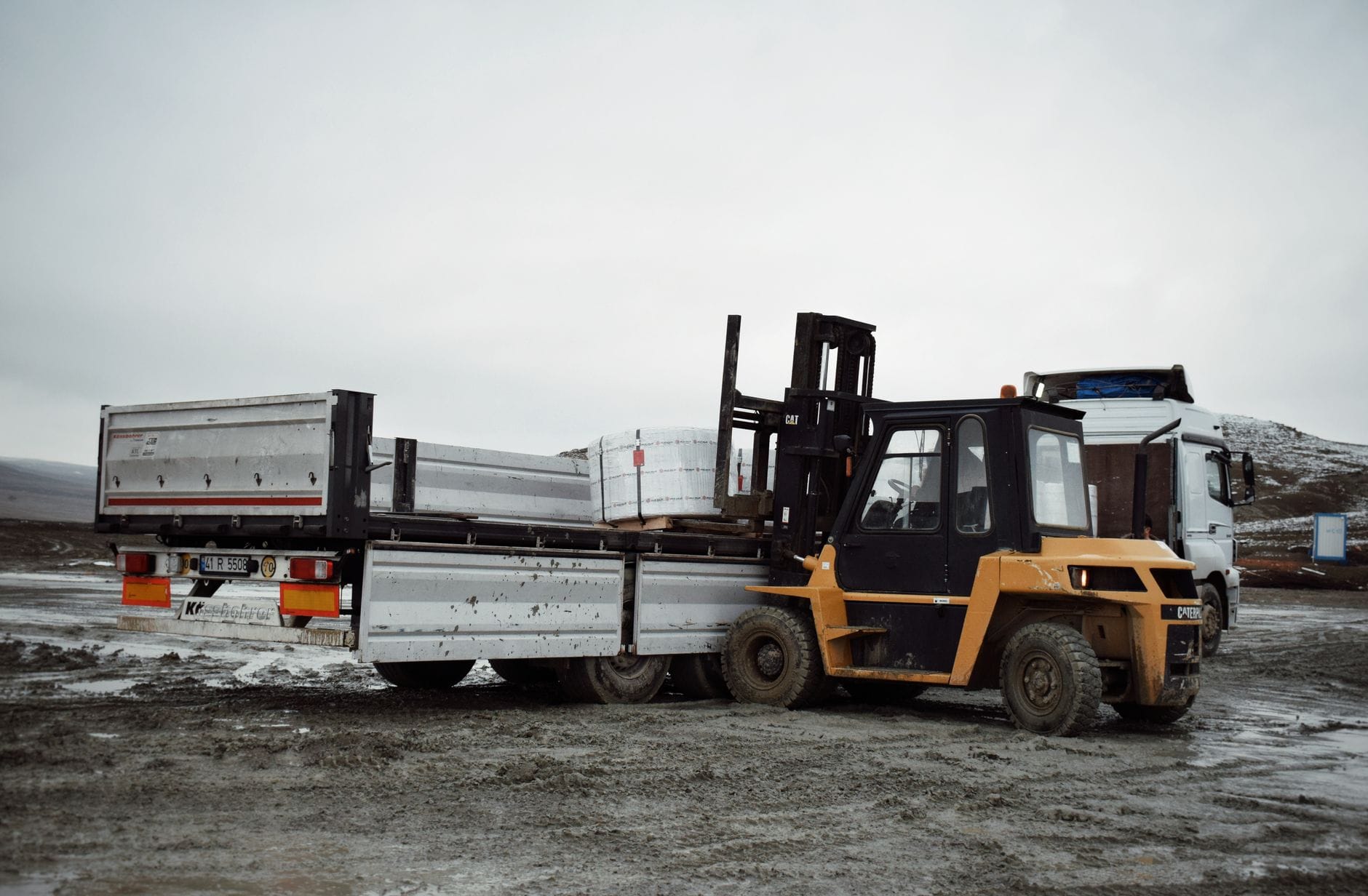Opony do wózków a osprzęt: jak dodatkowe obciążenia wpływają na zużycie Wózek widłowy ładuje materiały na ciężarówkę na terenie przemysłowym